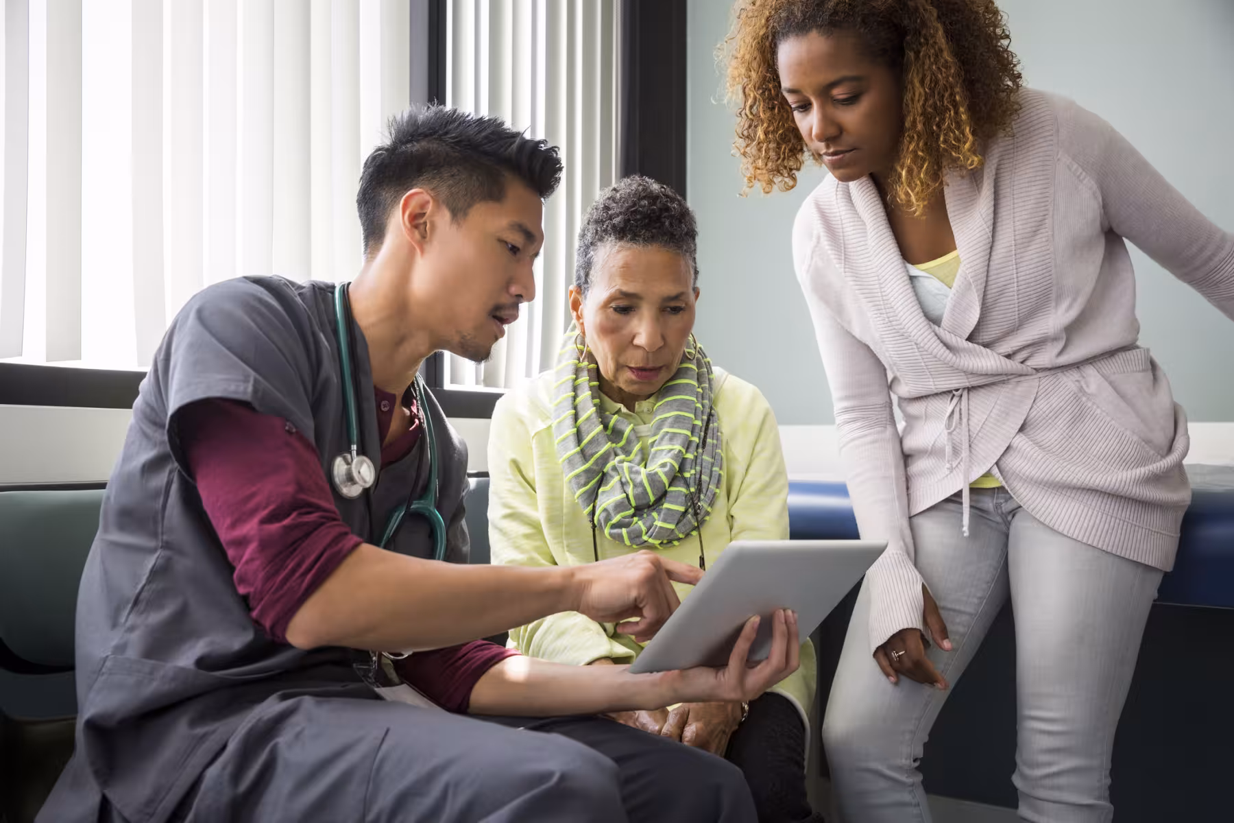 a doctor showing a tablet to two a patient and their family memeber